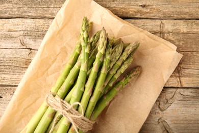 Bunch of fresh green asparagus stems on wooden table, top view