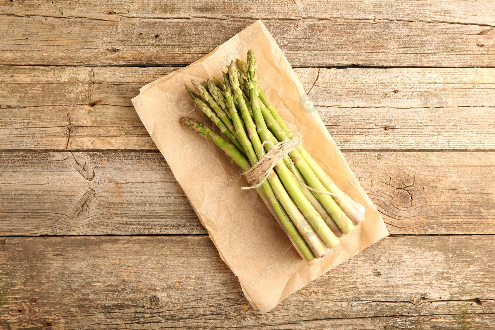 Photo of Bunch of fresh green asparagus stems on wooden table, top view