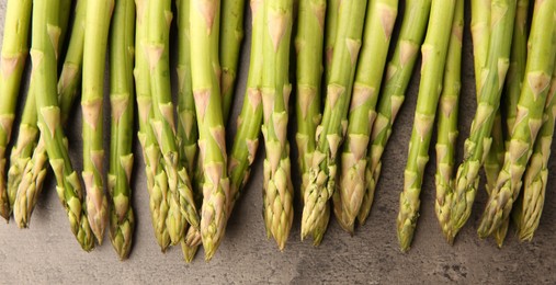 Fresh green asparagus stems on grey textured table, flat lay