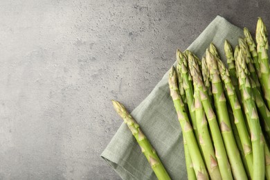 Photo of Fresh green asparagus stems on grey textured table, top view. Space for text