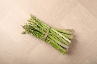 Photo of Bunch of fresh green asparagus stems on wooden table, top view