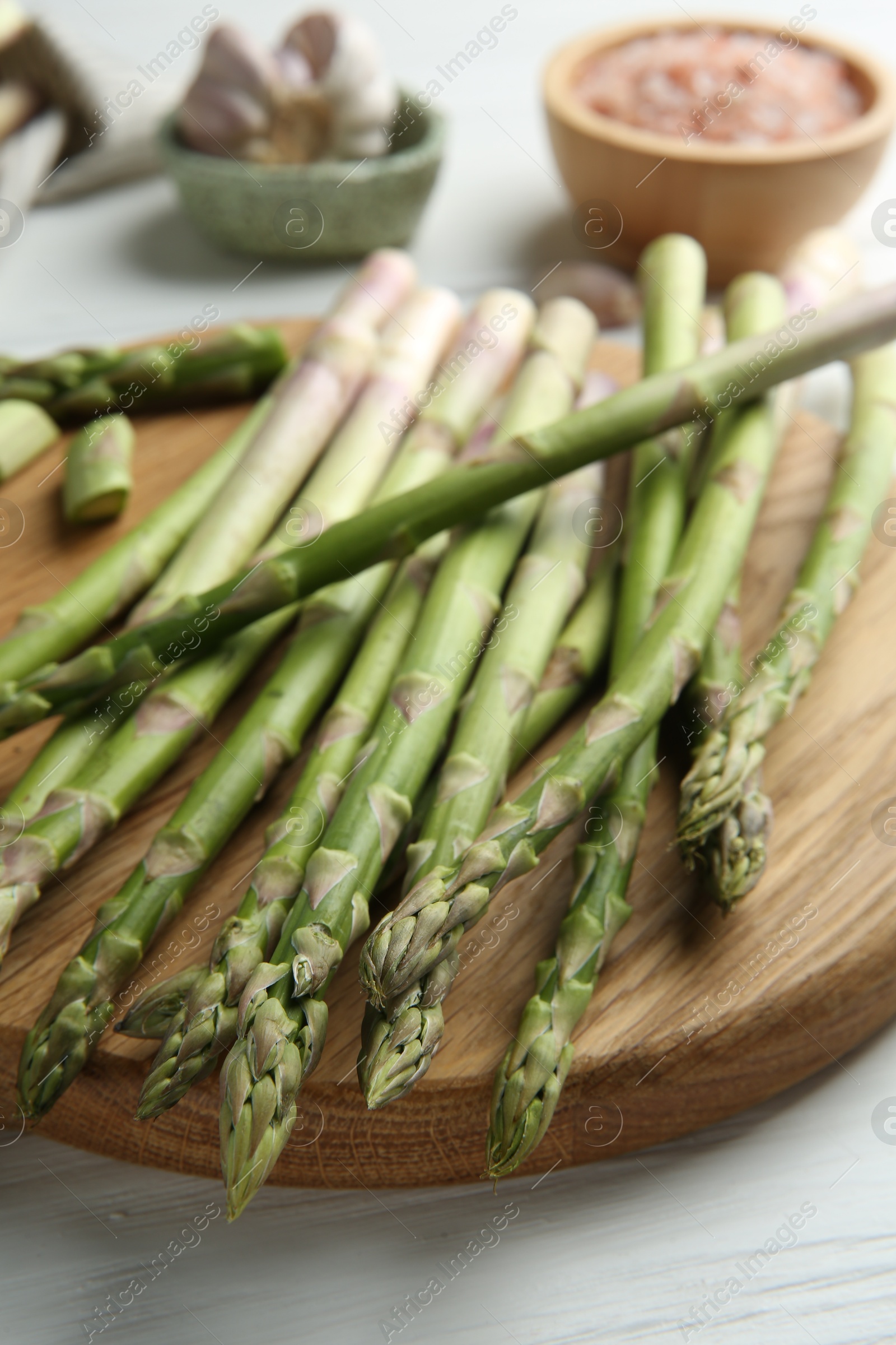 Photo of Fresh green asparagus stems on white wooden table, closeup