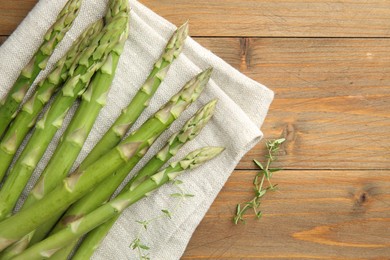 Photo of Fresh green asparagus stems and thyme on wooden table, top view