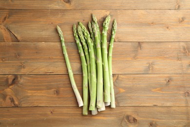 Photo of Fresh green asparagus stems on wooden table, top view