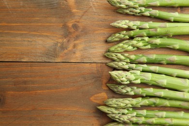 Fresh green asparagus stems on wooden table, top view. Space for text