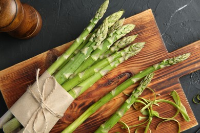 Photo of Fresh green asparagus stems and spices on gray textured table, flat lay