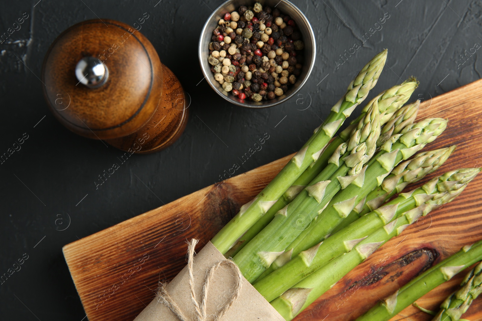 Photo of Fresh green asparagus stems and spices on gray textured table, flat lay