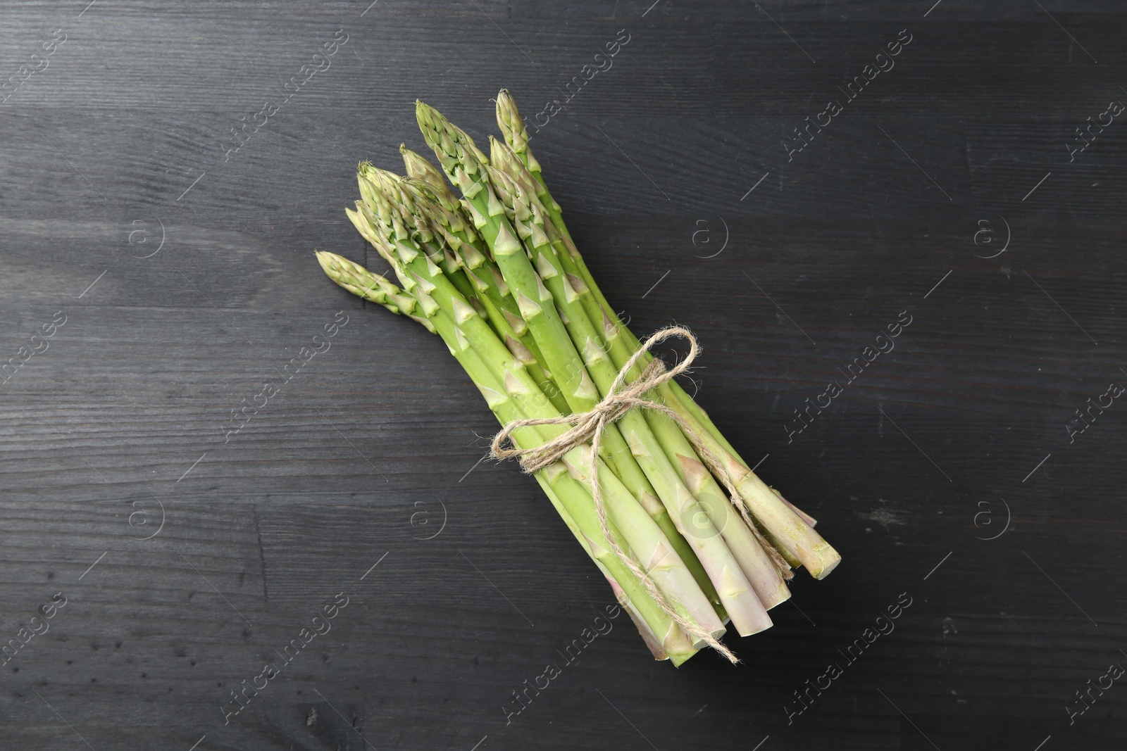 Photo of Bunch of fresh green asparagus stems on gray wooden table, top view