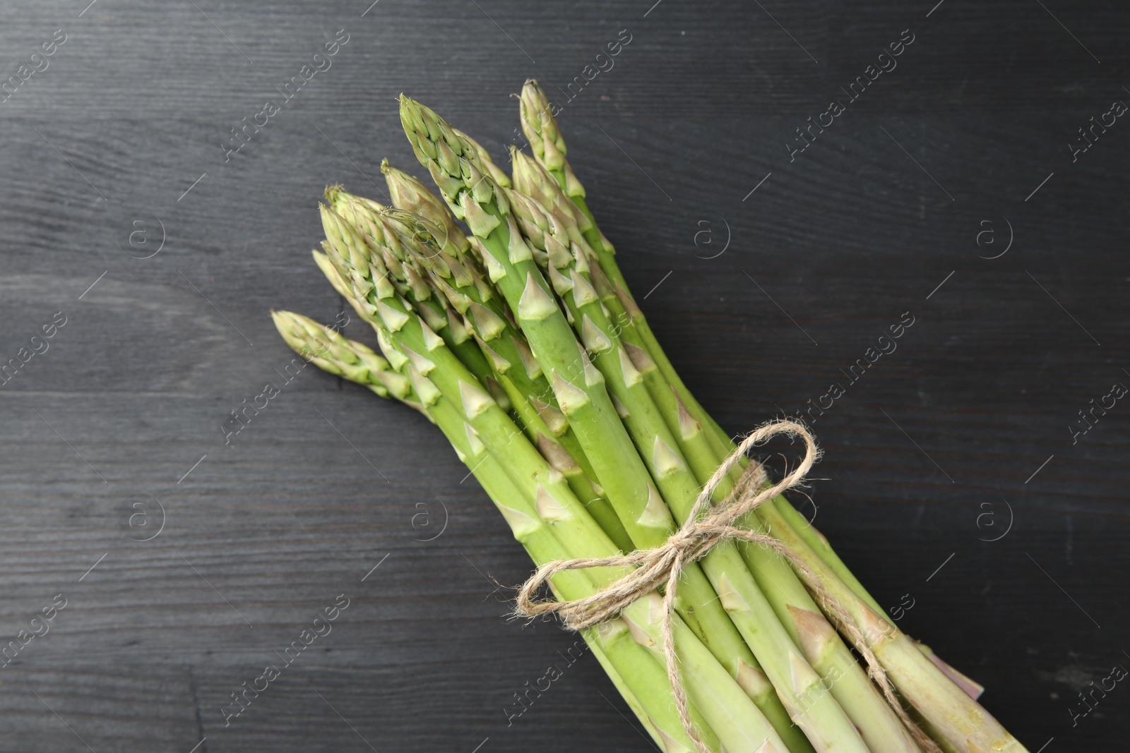 Photo of Bunch of fresh green asparagus stems on gray wooden table, top view