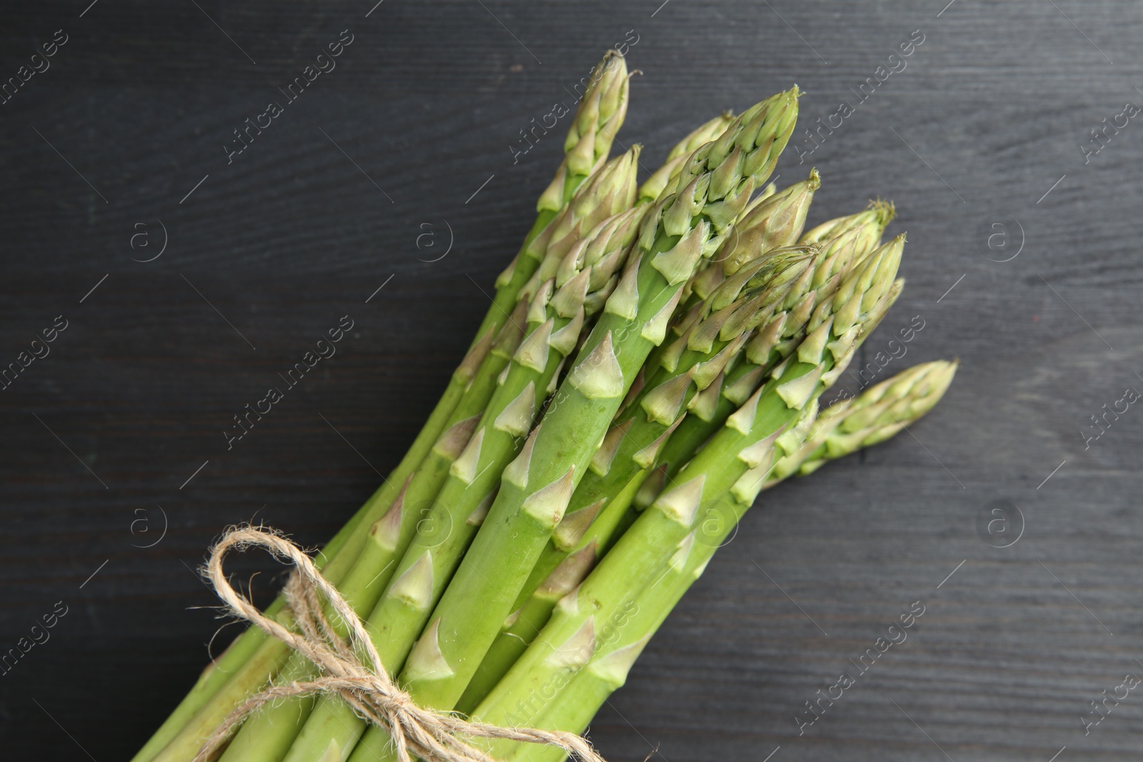 Photo of Bunch of fresh green asparagus stems on gray wooden table, top view