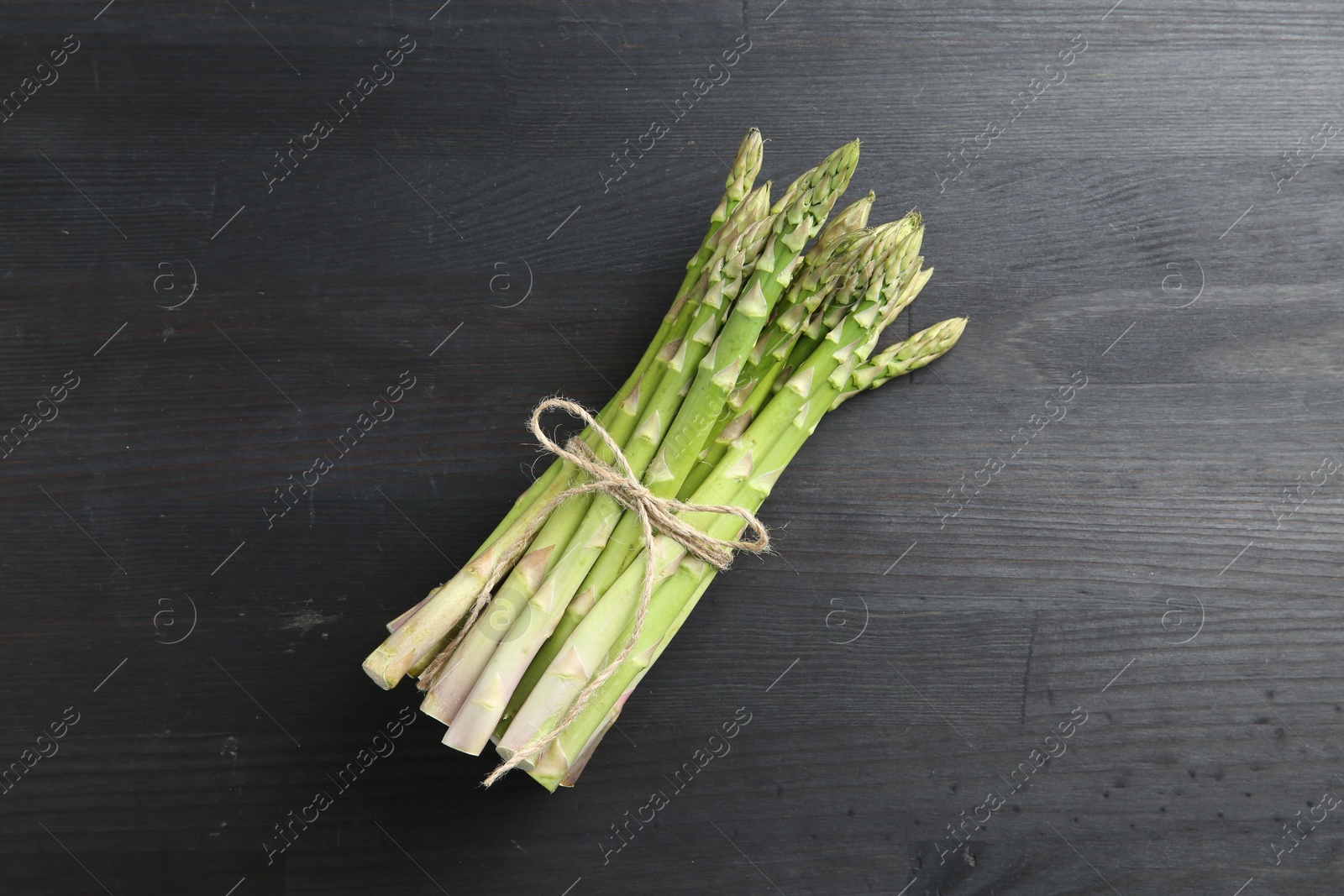 Photo of Bunch of fresh green asparagus stems on gray wooden table, top view