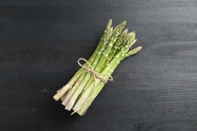 Photo of Bunch of fresh green asparagus stems on gray wooden table, top view