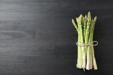 Photo of Bunch of fresh green asparagus stems on gray wooden table, top view. Space for text