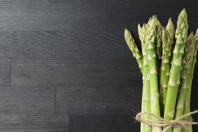 Photo of Bunch of fresh green asparagus stems on gray wooden table, top view. Space for text