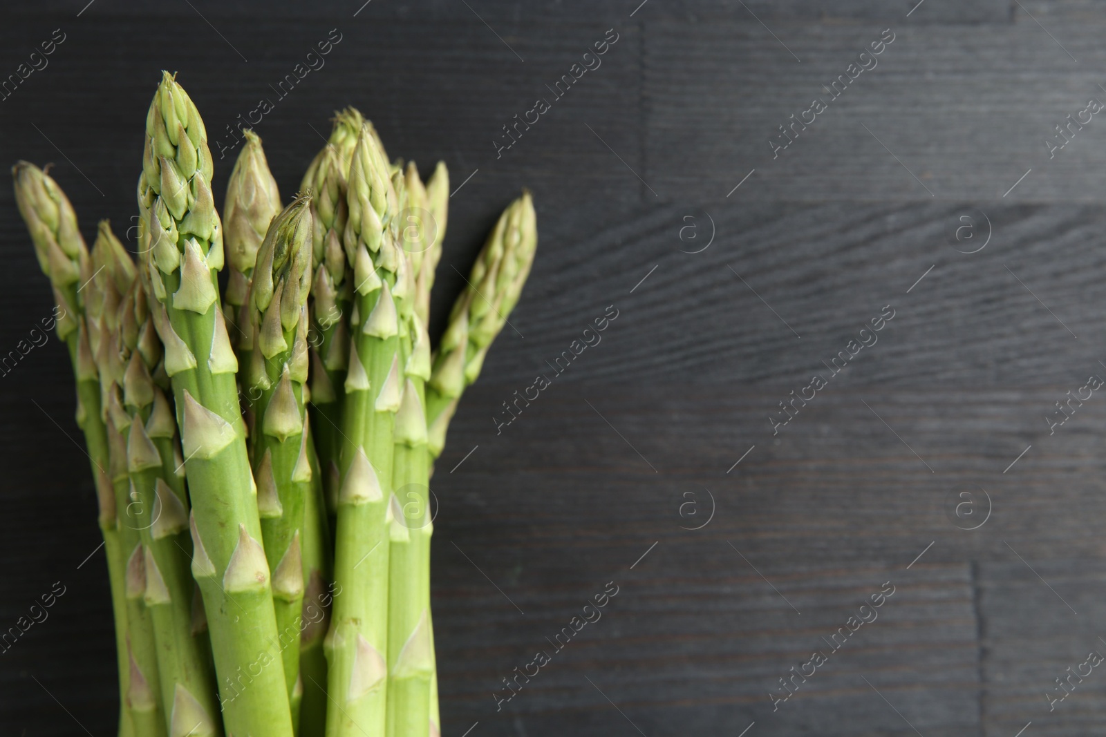 Photo of Fresh green asparagus stems on gray wooden table, top view. Space for text