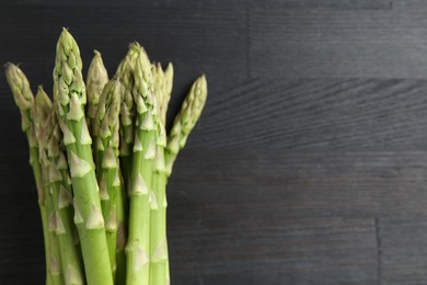 Photo of Fresh green asparagus stems on gray wooden table, top view. Space for text