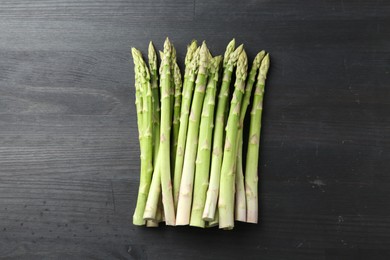 Photo of Fresh green asparagus stems on gray wooden table, top view