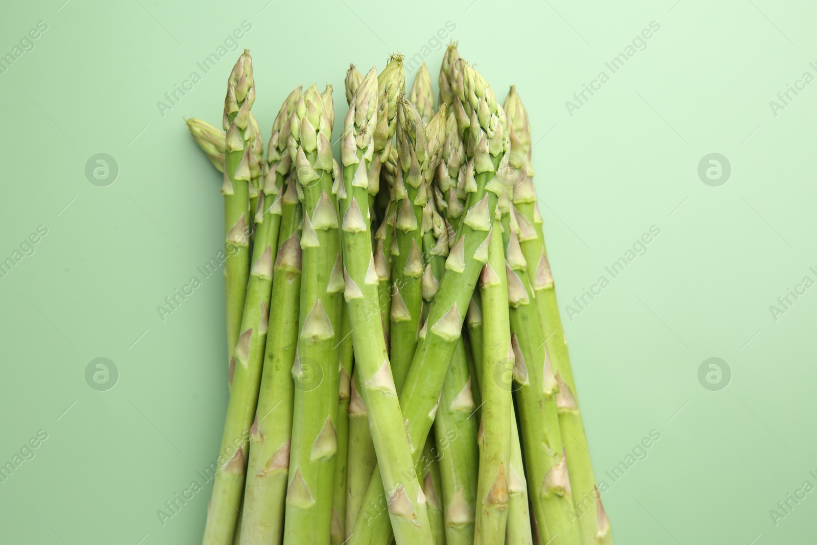 Photo of Fresh asparagus stems on green table, top view