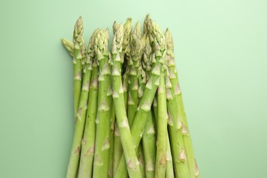 Fresh asparagus stems on green table, top view