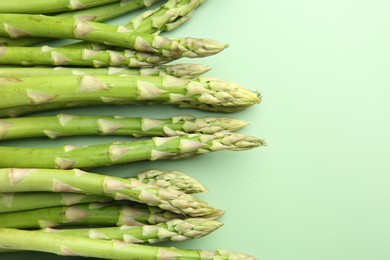 Photo of Fresh asparagus stems on green table, top view. Space for text