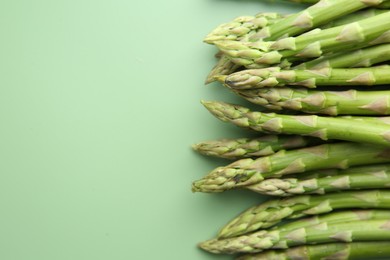 Photo of Fresh asparagus stems on green table, top view. Space for text