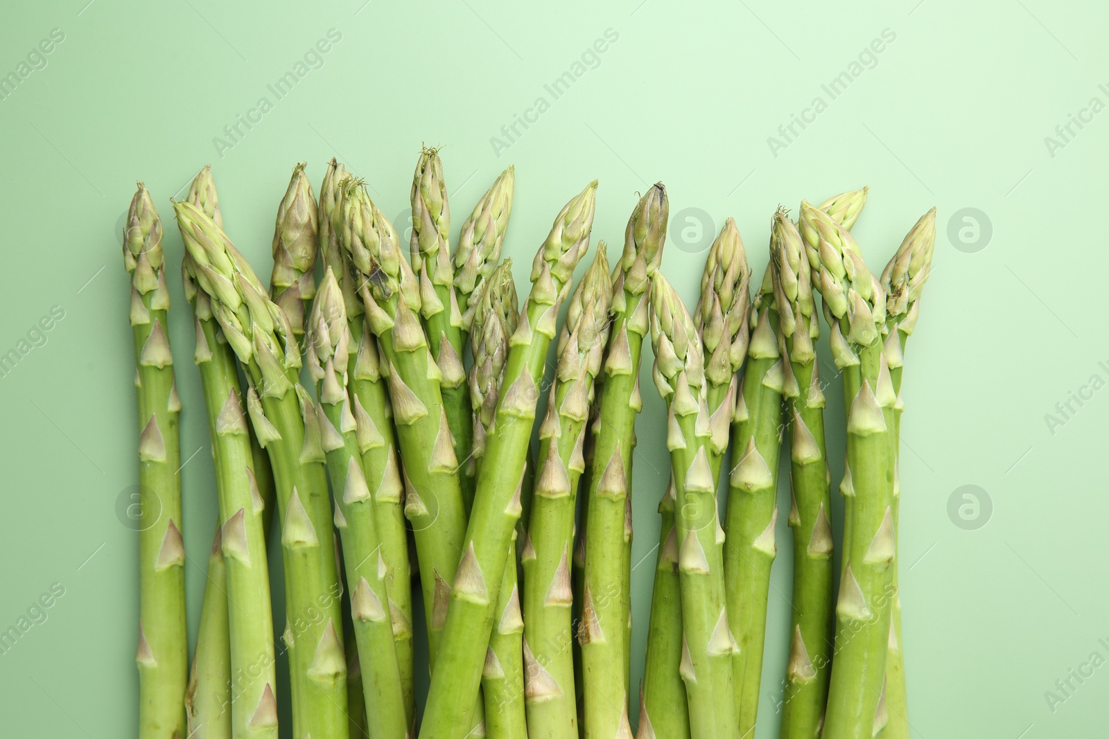 Photo of Fresh asparagus stems on green table, top view