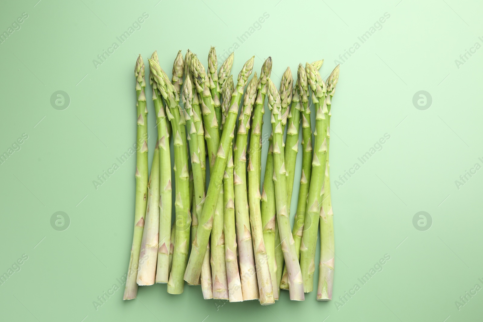 Photo of Fresh asparagus stems on green table, top view