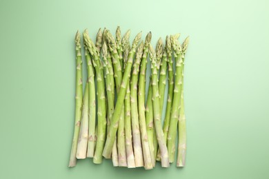 Photo of Fresh asparagus stems on green table, top view