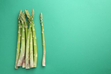 Fresh green asparagus stems on turquoise table, top view. Space for text