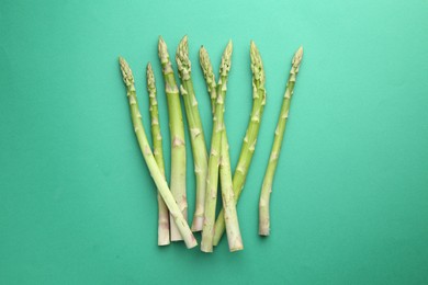 Fresh green asparagus stems on turquoise table, top view