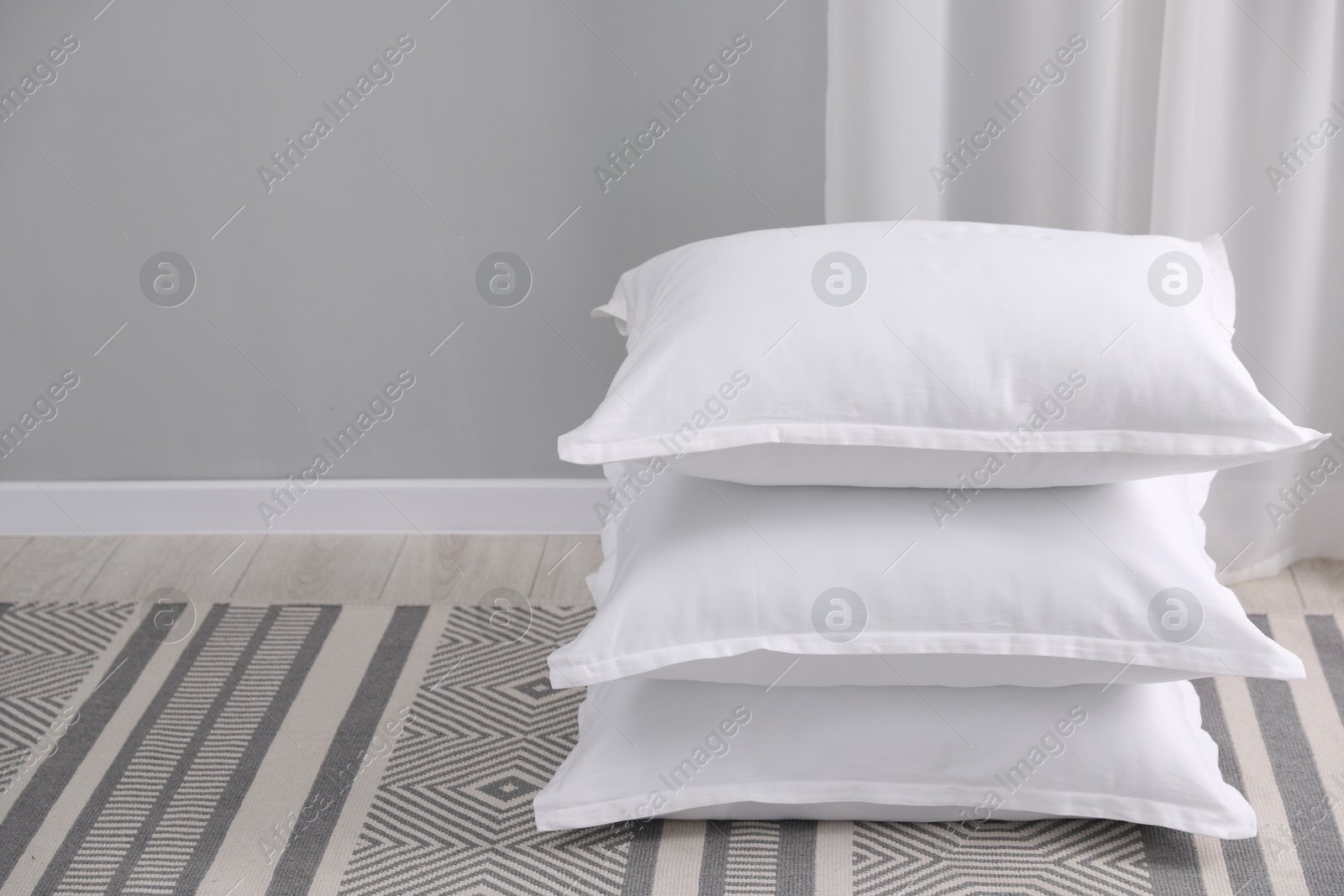 Photo of Stack of white pillows on floor indoors. Space for text