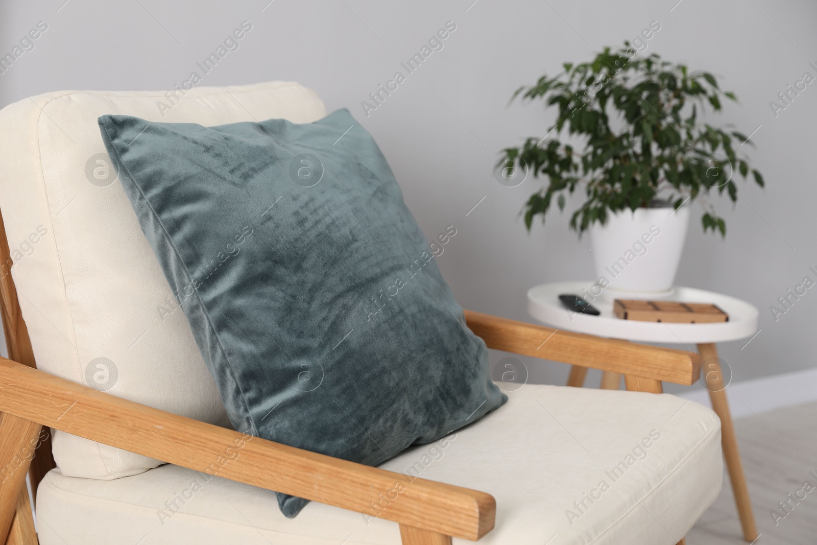 Photo of Soft pillow on armchair near coffee table indoors