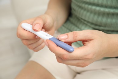 Photo of Woman holding pregnancy test indoors, closeup view