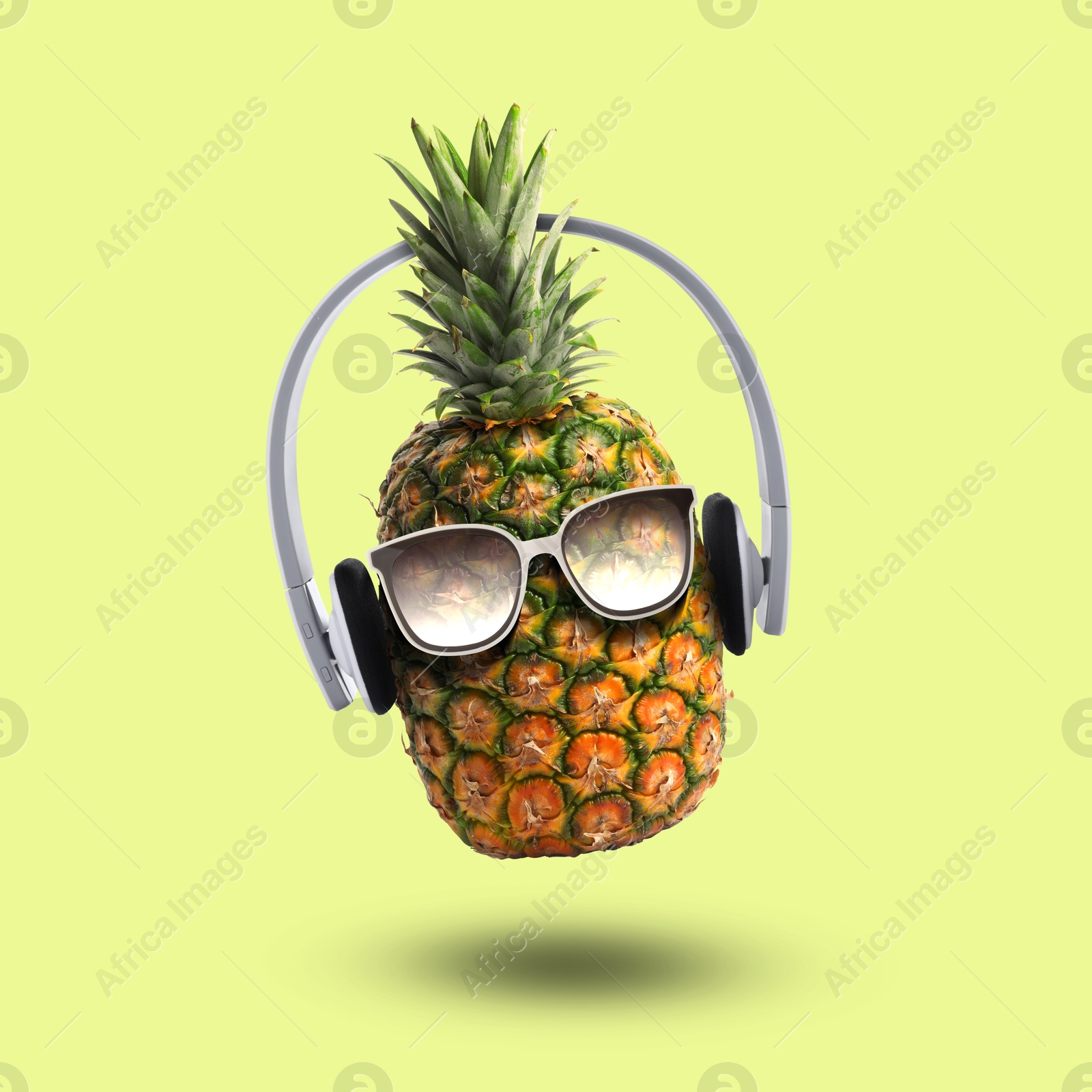 Image of Summer vibe. Pineapple with sunglasses and headphones on yellowish green background. Party flyer or other seasonal