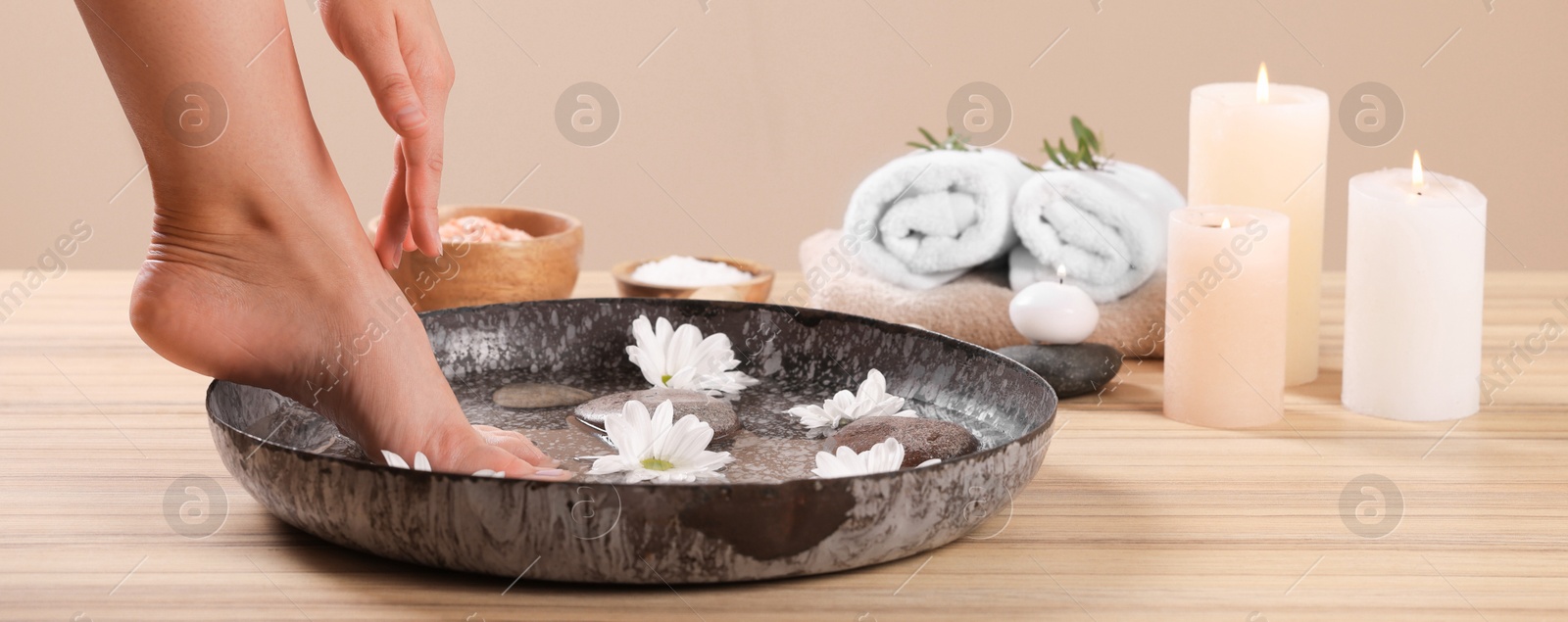 Image of Woman having pedicure procedure on wooden floor, closeup. Banner design