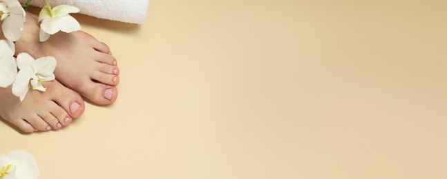 Woman showing neat toenails after pedicure procedure and flowers on beige background, top view. Banner design with space for text