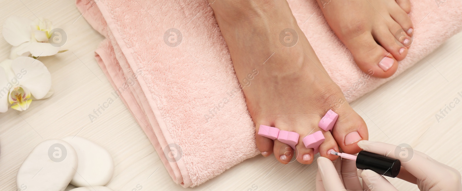 Image of Pedicurist painting client`s toenails with polish, top view. Banner design