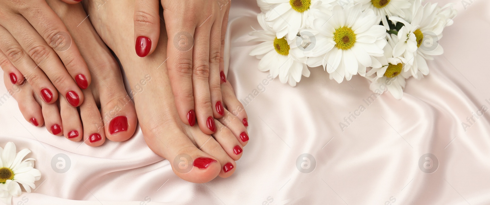 Image of Woman showing neat toenails and fingernails after pedicure and manicure procedures and flowers on silky fabric, closeup. Banner design