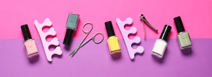 Nail polishes, clippers, scissors and toe separators on color background, flat lay. Banner design