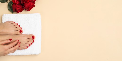 Woman showing neat toenails and fingernails after pedicure and manicure procedures and flowers on beige background, top view. Banner design with space for text