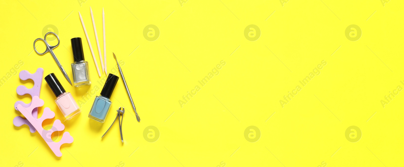 Image of Nail polishes and set of pedicure tools on yellow background, flat lay. Banner design with space for text