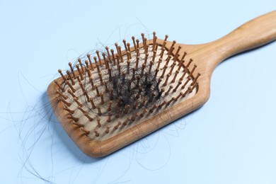 Wooden brush with lost hair on light blue background