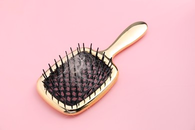 Photo of Brush with lost hair on pink background