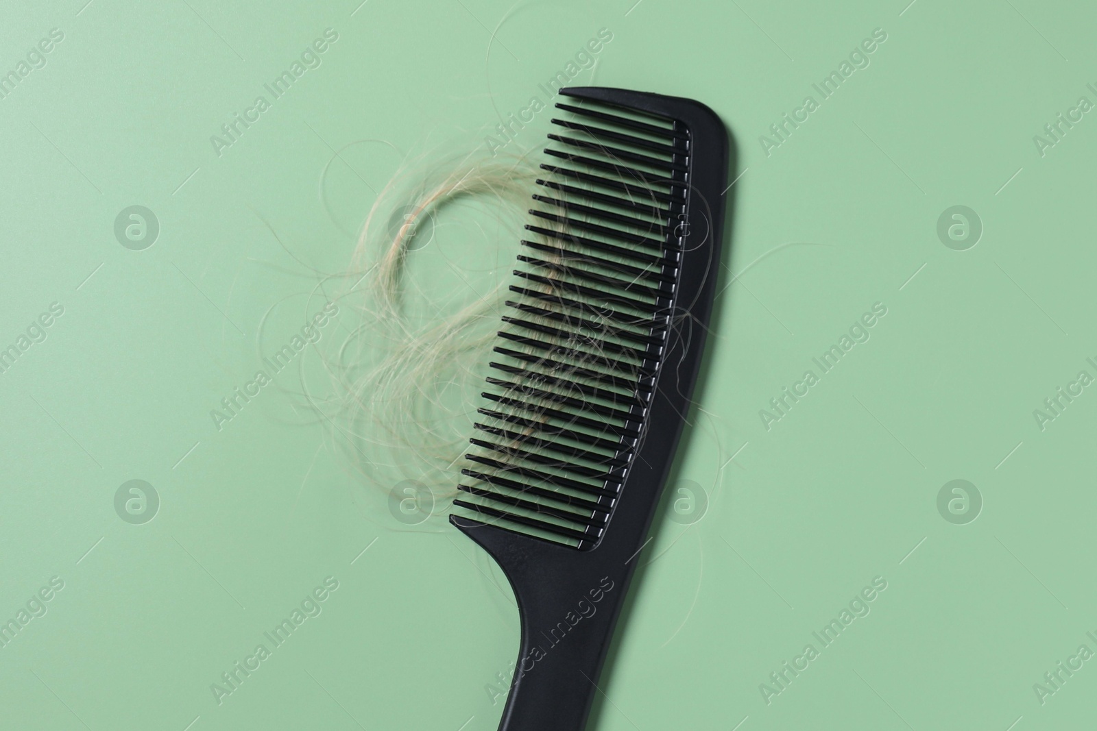 Photo of Comb with lost hair on green background, top view