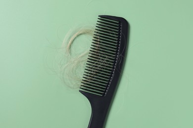 Photo of Comb with lost hair on green background, top view