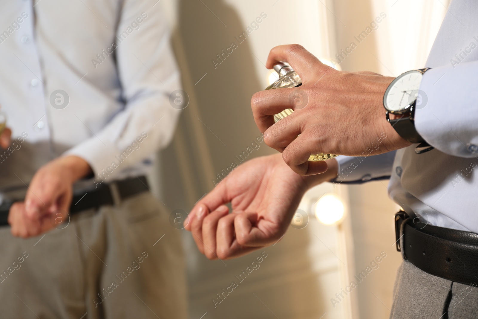 Photo of Man spraying luxury perfume near mirror indoors, closeup