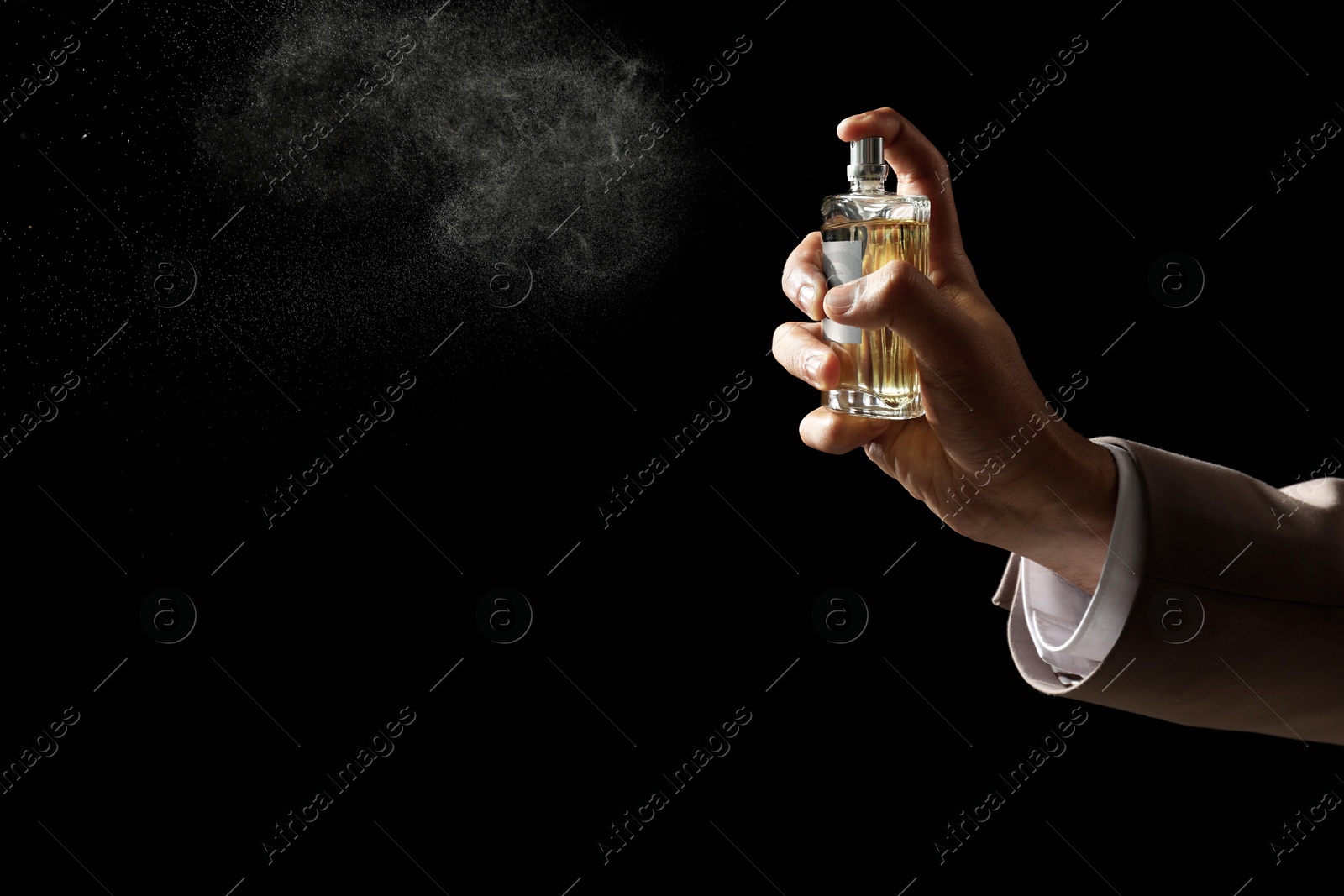 Photo of Man spraying luxury perfume on dark background, closeup. Space for text