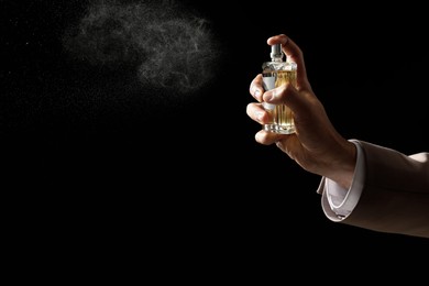 Man spraying luxury perfume on dark background, closeup. Space for text