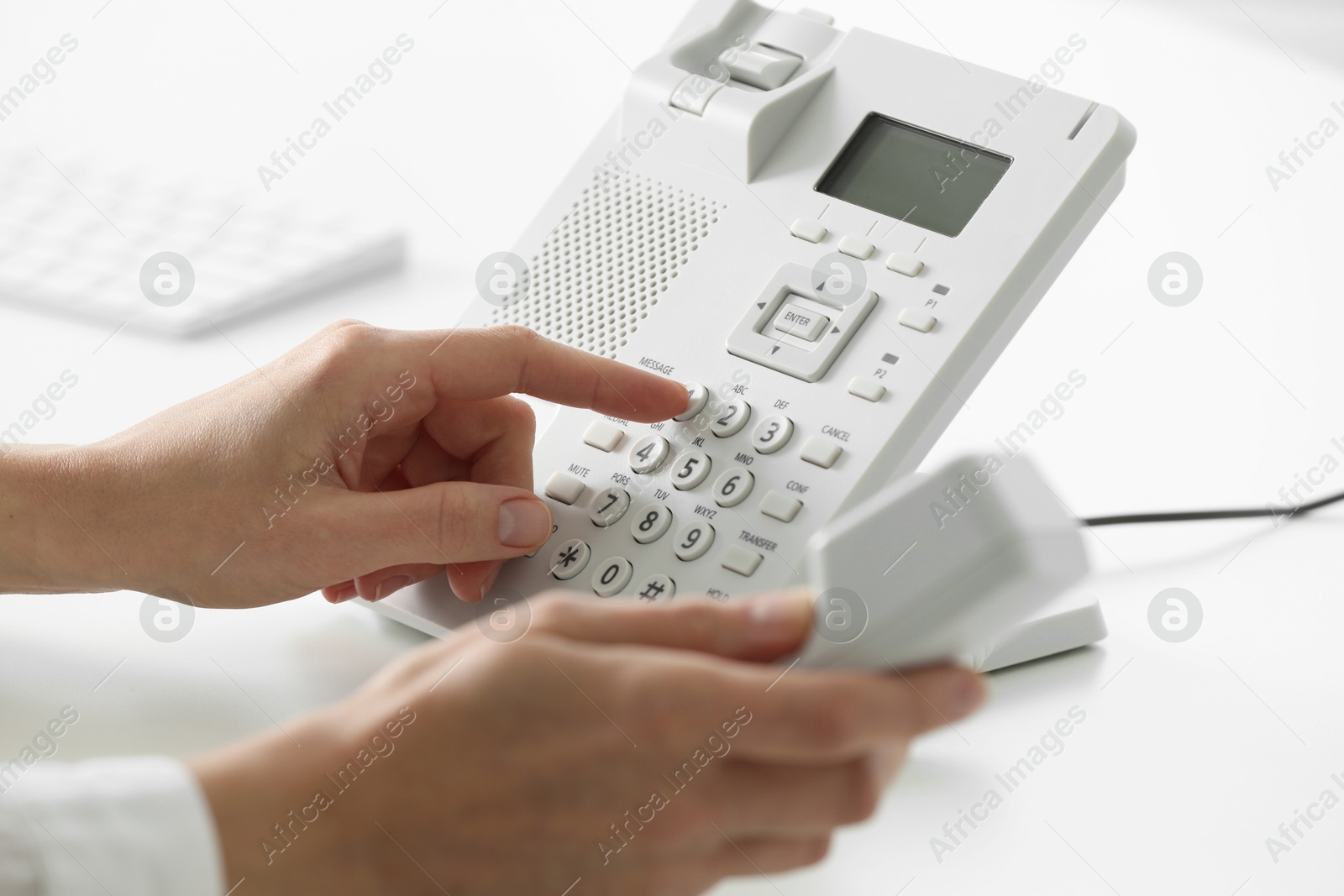 Photo of Assistant dialing number on telephone against blurred background, closeup