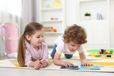 Cute little children reading book on floor in kindergarten